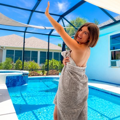 Cassie smiling and waving in front of a swimming pool